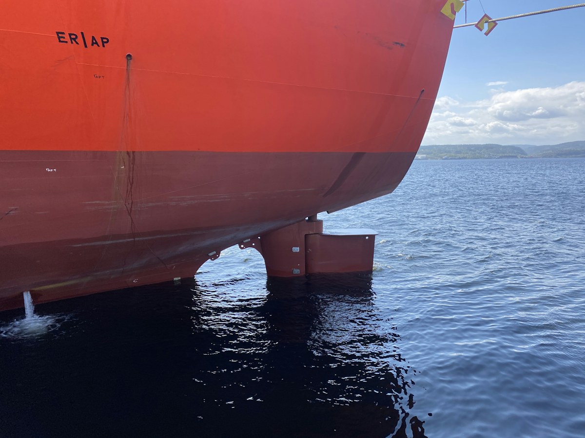 The stern of a ship riding high in calm water, its rudder clear of the surface